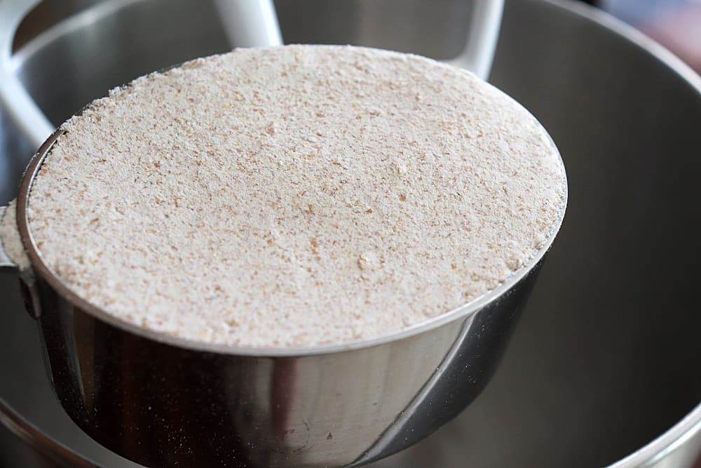 Adding whole wheat flour to the bowl of an electric mixer